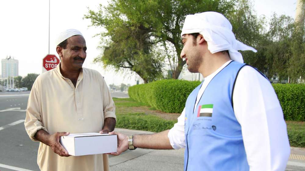 A volunteer hands out an Iftar meal in Mushrif Mall area, Abu Dhabi